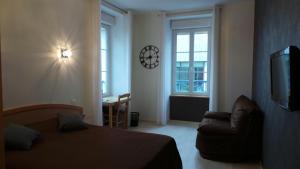 a bedroom with a bed and a chair and a clock at Hotel La Renaissance in Cherbourg en Cotentin