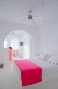a white bedroom with a large bed with a pink blanket at Notos Therme and Spa in Vlychada
