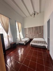 イキケにあるHostal Casa Norteの赤いタイルフロアのベッドルーム1室(ベッド2台付)