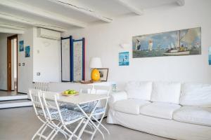 a living room with a white couch and a table and chairs at Caletta Nest 108 in Porto Rotondo