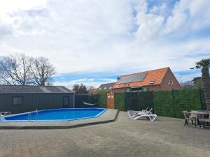a backyard with a swimming pool and a house at Vakantiehuis De Hut in Oostkapelle