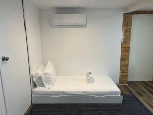 a white room with a bed with white pillows at Cozy 2Beds Studio witch Kitchen Laundry near Zoo and Mall in Jindalee