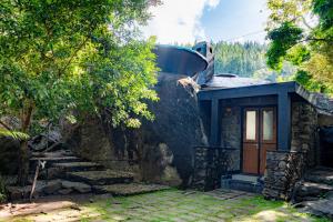 ein Haus mit einer Steinmauer und einer Tür in der Unterkunft Forest Heaven Eco Resort in Belihuloya