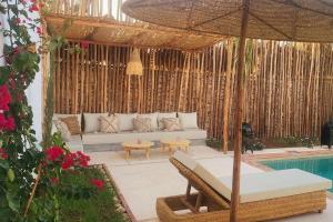 a patio with a couch and an umbrella and a pool at Villa Dar Mira - Ghazoua Essaouira in Ghazoua