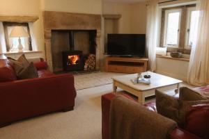 ein Wohnzimmer mit Kamin, Sofas und Fernseher in der Unterkunft Primrose cottage in Buxton