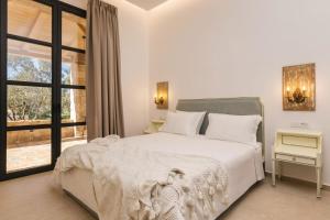 una camera da letto bianca con un letto grande e una finestra di Le tresor de Marie - Charming Traditional Retreat, by ZanteWize a Gaïtánion Altre 42 foto