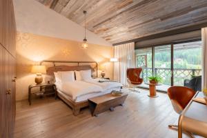 a bedroom with a bed and a table and chairs at Valsana Hotel Arosa - Small Luxury Hotels of the World in Arosa