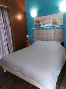 a bedroom with a white bed with a blue wall at La Tour de Jeanne, à 10 minutes de Saint-Emilion in Gardegan-et-Tourtirac