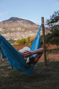 a woman sitting in a hammock in a field at Pousada Lapinha Da Serra 1 - Chalés Independentes e Privativos - Liberdade e Conforto na natureza in Santana do Riacho