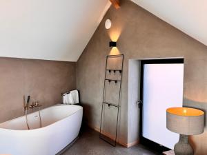 a bathroom with a large white tub in a attic at Basse Cour in Durbuy