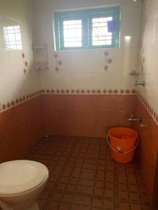 a bathroom with a toilet and an orange bucket at Holiday homes by Friday Retreats in Pīrmed