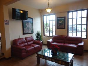 a living room with two leather couches and a tv at Hotel El Cafetalero in Xicotepec de Juárez