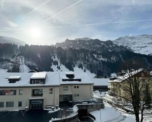 a building with snow on the roof with a mountain at Apartment 302 - Zentrales Studio in Engelberg