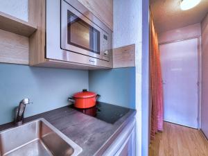 a small kitchen with a red pot on the counter at Studio Soyouz Vanguard-102 by Interhome in Le Corbier