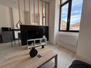 a living room with a tv and a coffee table at Appartement rénové, proche gare in Bourg-de-Péage