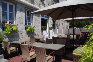an outdoor patio with tables and chairs and umbrellas at Hotel Val Saint Hilaire in Givet
