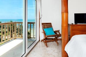 Cette chambre dispose d'un balcon avec une chaise et une télévision. dans l'établissement Residences at Barrier Reef 1-3C Oceanfront 2 BR by Stay Floreo, à San Pedro