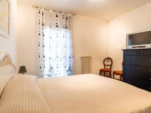 a bedroom with a bed and a television and a dresser at Apartment le Mimose by Interhome in Taggia