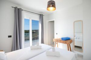 una camera bianca con una grande finestra e un letto di Villa Antreas Mentoros a Karavádhos Altre 25 foto