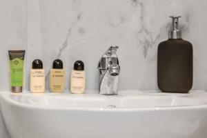 a bathroom sink with four perfume bottles on it at Cozy Sunlit Studio with Kitchenette in London +19 photos