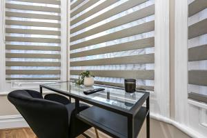 a glass table and chairs in a room with blinds at Cozy Sunlit Studio with Kitchenette in London