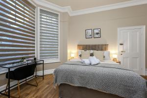 a bedroom with a bed and a desk and windows at Cozy Sunlit Studio with Kitchenette in London