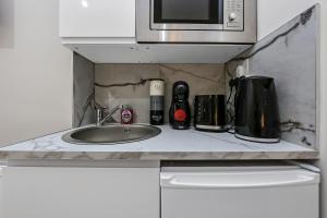 a kitchen counter with a sink and a microwave at Cozy Sunlit Studio with Kitchenette in London