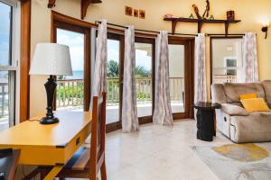 a living room with a desk and a chair and windows at Residences at Barrier Reef 3B Oceanview 2 BR by Stay Floreo in San Pedro