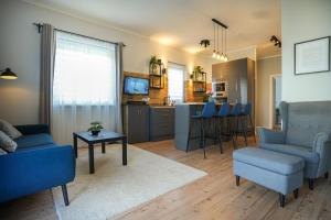 a living room with blue chairs and a kitchen at Messzikék in Egerszalók