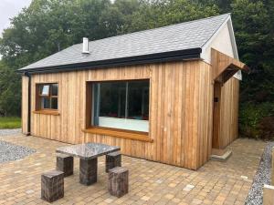um pequeno barracão de madeira com um banco e uma mesa em Cosy Studio Cabin set in nature with stove em Killybegs