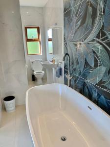 um banheiro branco com banheira e pia em Cosy Studio Cabin set in nature with stove em Killybegs