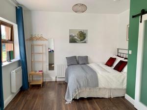 um quarto com uma cama com almofadas vermelhas e cinzentas em Cosy Studio Cabin set in nature with stove em Killybegs