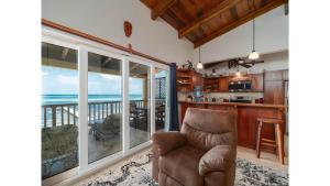 a living room with a chair and a view of the ocean at Residences at Barrier Reef 1-2C Oceanfront 2 BR by Stay Floreo in San Pedro