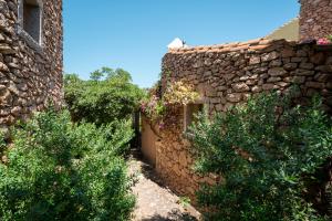 a stone building with bushes next to a stone wall at Caletta Nest 88 in Porto Rotondo