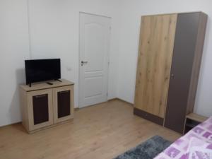 a room with a tv on a stand next to a door at Pensiunea Casa Lircă in Topliţa