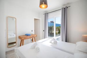 una camera da letto bianca con due letti e uno specchio di Villa Katerina Mentoros a Karavádhos Altre 28 foto