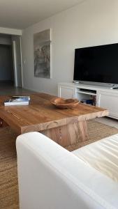 un salon avec une table basse en bois et une télévision à écran plat dans l'établissement Esturion de Montoya, à Punta del Este 18 autres photos