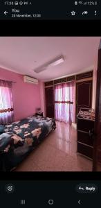 a bedroom with a bed and pink walls and windows at villa jam in Pamplemousses Village