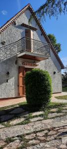 una casa con balcone e un cespuglio di fronte ad essa di Villa Anna a San Venanzo