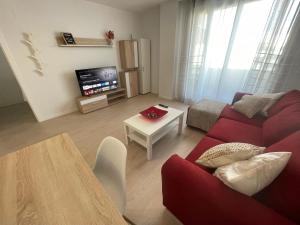 a living room with a red couch and a table at M3 Rivas Futura Apartment in Rivas-Vaciamadrid