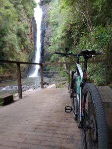 a bike parked on a bridge near a waterfall at Chalé Cafofo in Campo Alegre