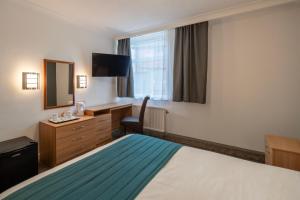 a hotel room with a bed and a desk and a mirror at Britannia Hotel Bolton in Bolton