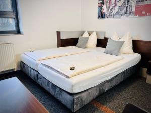 a bedroom with a bed with white sheets and pillows at Jugendherberge City-Hostel Köln-Riehl in Cologne