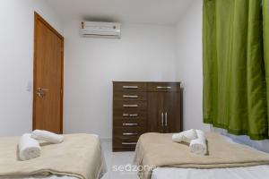 a room with two beds and a dresser and green curtains at Apto Cond Vog, Ilhéus, a 5 Min da Praia! - VTL0103 in Pontal +19 photos