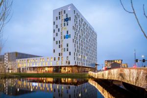 a tall white building next to a body of water at Novotel Amsterdam Schiphol Airport in Hoofddorp