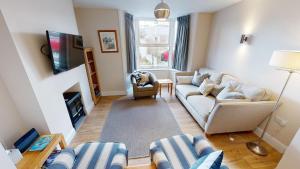 ein Wohnzimmer mit zwei Sofas und einem Fernseher in der Unterkunft Holmdean Cottage in Sidmouth