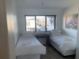 two beds in a room with a window at At Sea, Melkbosstrand in Melkbosstrand