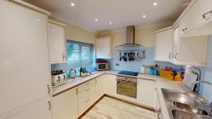 シドマスにあるThe Crows Nestの白いキャビネットとシンクのあるキッチン