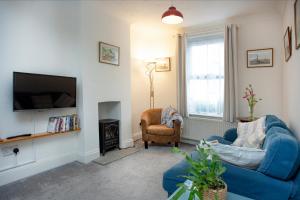 ein Wohnzimmer mit einem blauen Sofa und einem Fernseher in der Unterkunft Salty Cottage in Sidmouth