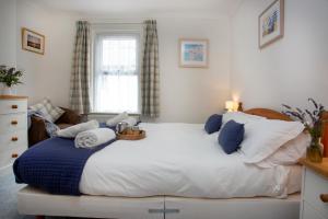 ein Schlafzimmer mit einem großen weißen Bett mit blauen Kissen in der Unterkunft Salty Cottage in Sidmouth